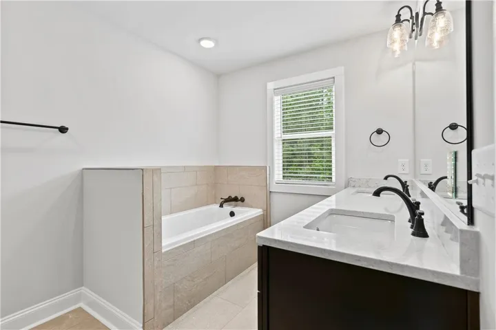 This angle of the spacious primary bathroom shows off the elegant finishes and a relaxing soaking tub, creating a serene personal retreat.