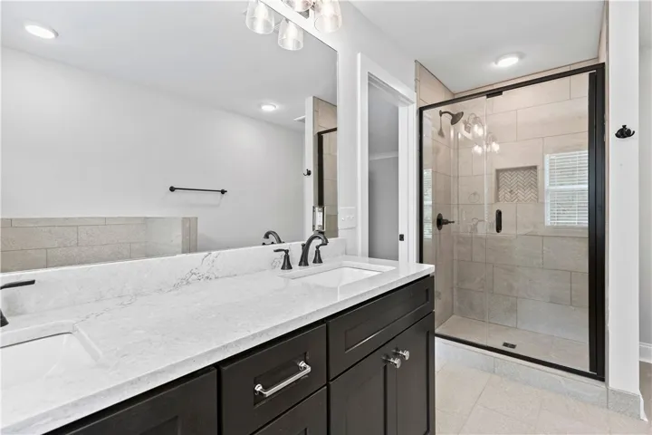 This primary bathroom features an expansive vanity and a glass-enclosed shower for a clean, modern aesthetic.