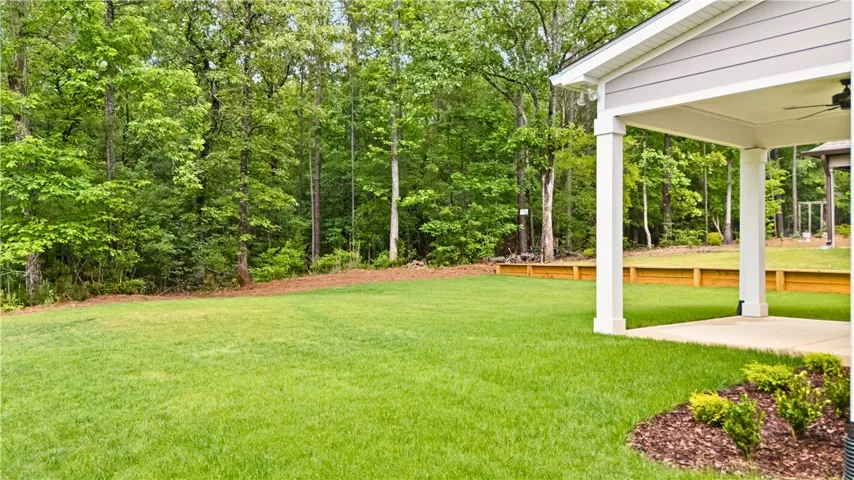Another angle of the back yard showing the lush green lawn and features a covered patio perfect for outdoor enjoyment.