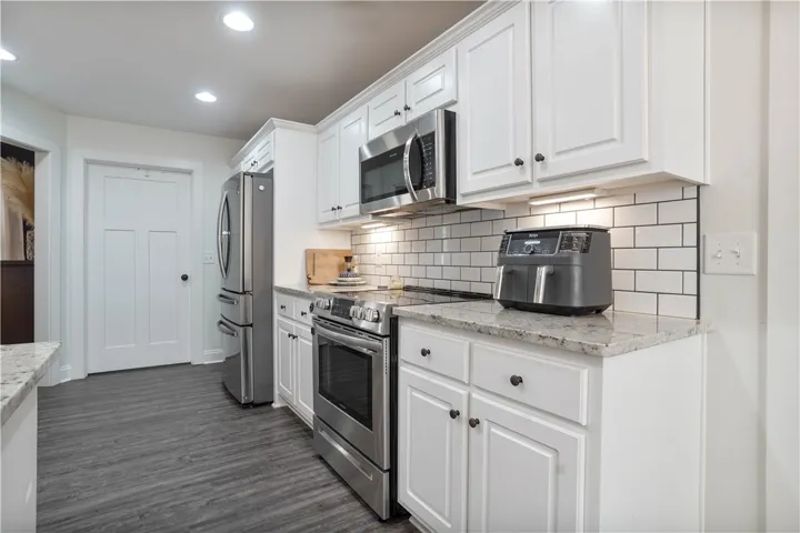 Open Concept Kitchen with Tile BackSplash, White Cabinets, & LVP throughout all the common areas