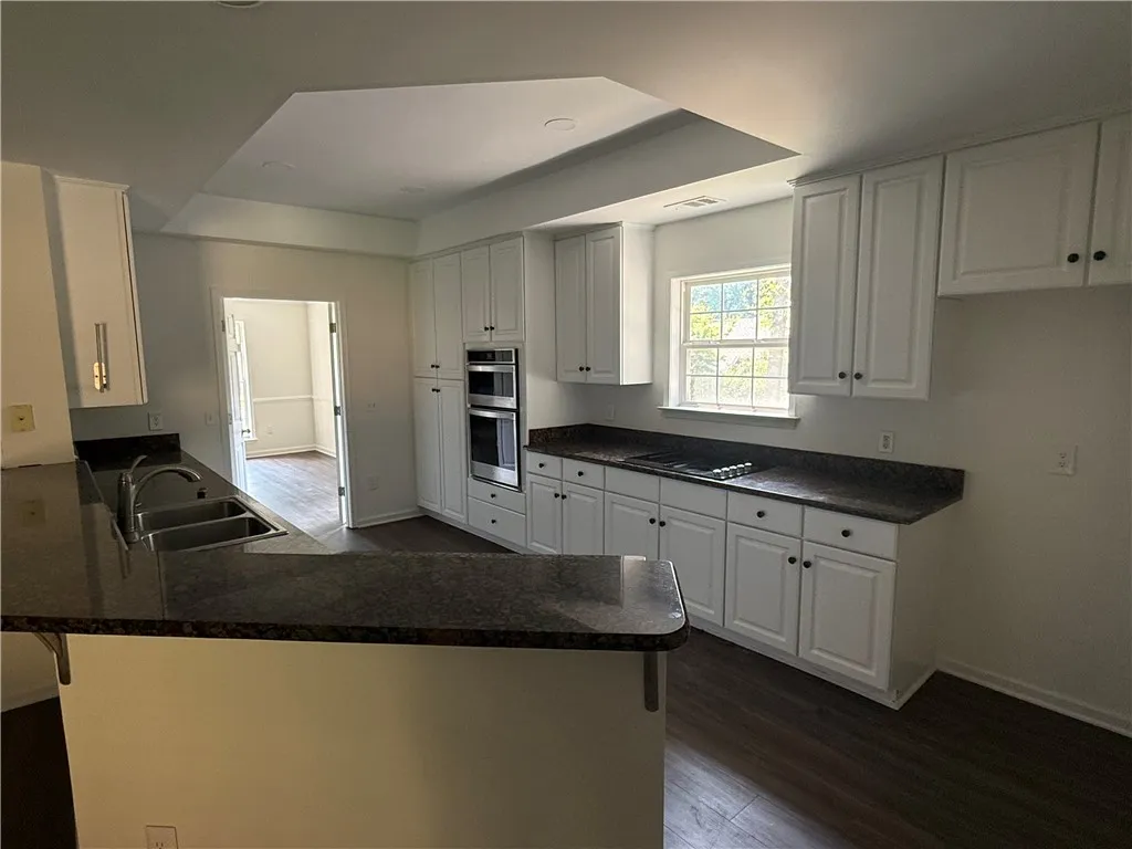 This newly renovated kitchen features sleek white cabinetry and elegant dark granite countertops, offering both style and functionality.