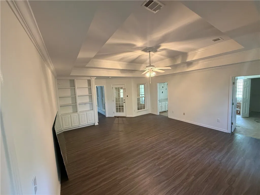 Built-in shelving, tray ceilings, and an overhead fan define this inviting living space.