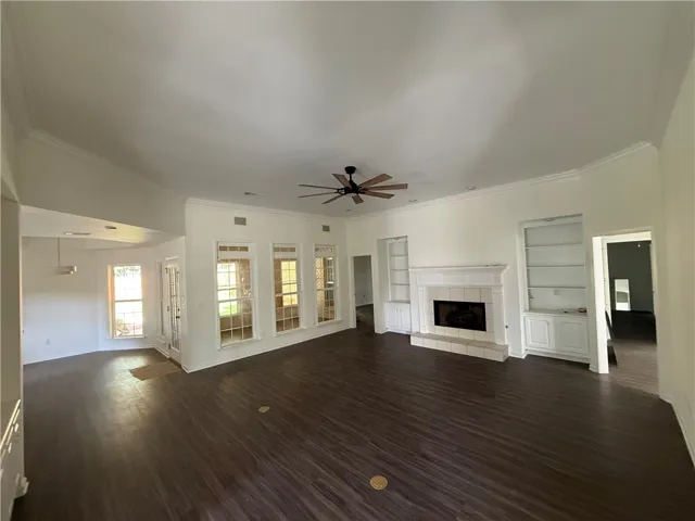 A spacious living area features elegant crown molding, a cozy fireplace, and custom built-in shelving.
