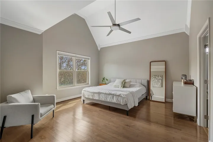 This primary bedroom  is flooded with natural light and boasts soaring ceilings. The ceiling fan is so sheik.