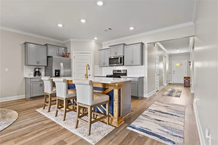 A stunning statement island anchors the kitchen with generous seating, substantial workspace, and custom designer detailing that brings warmth, contrast, and elevated style.