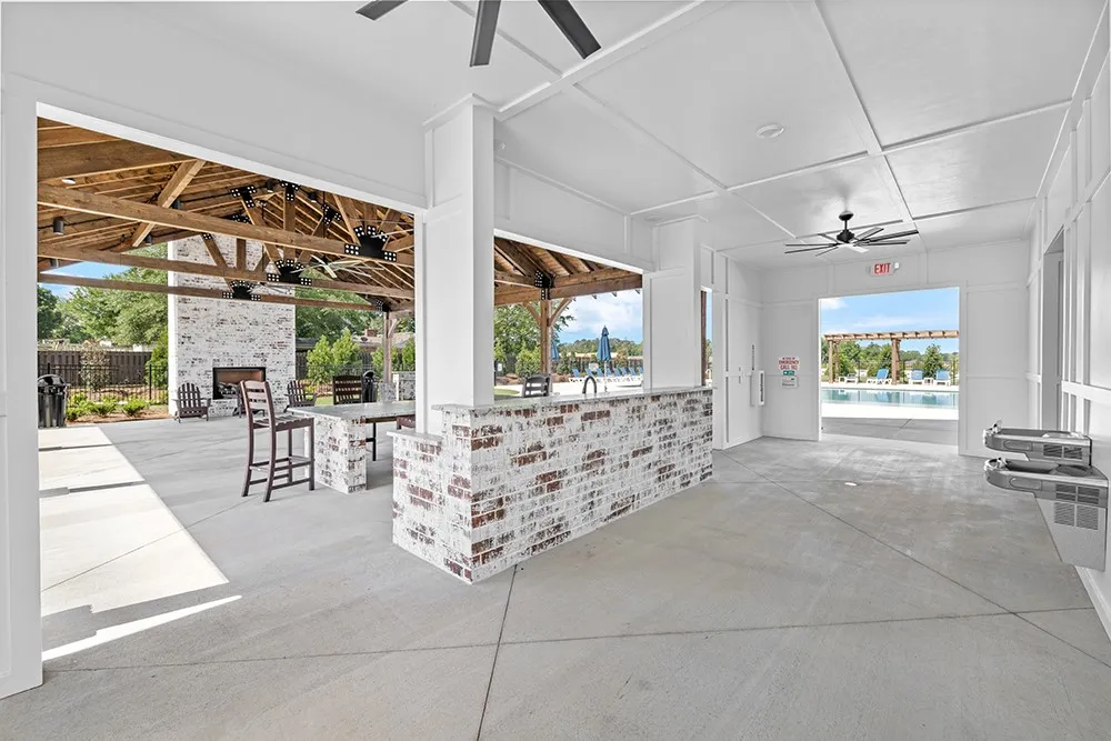 An inviting open-air lounge with a brick bar overlooks a refreshing community pool.