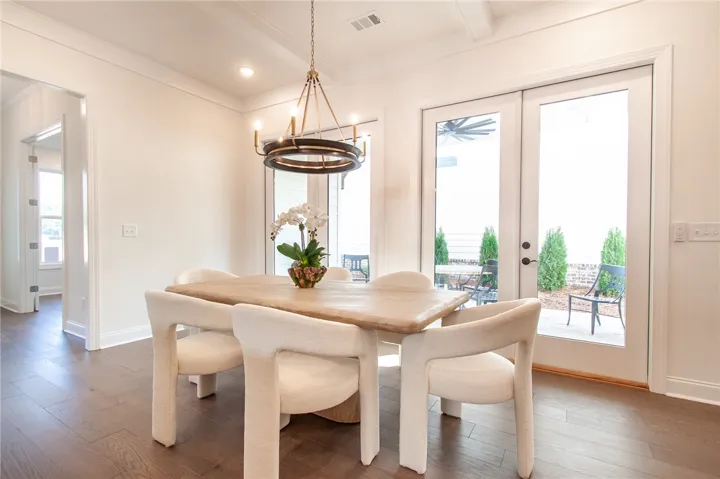 This bright dining area features French doors and rich hardwood flooring, perfect for gatherings. Photos are not of subject property. Photos are of the same floorplan of a completed home.