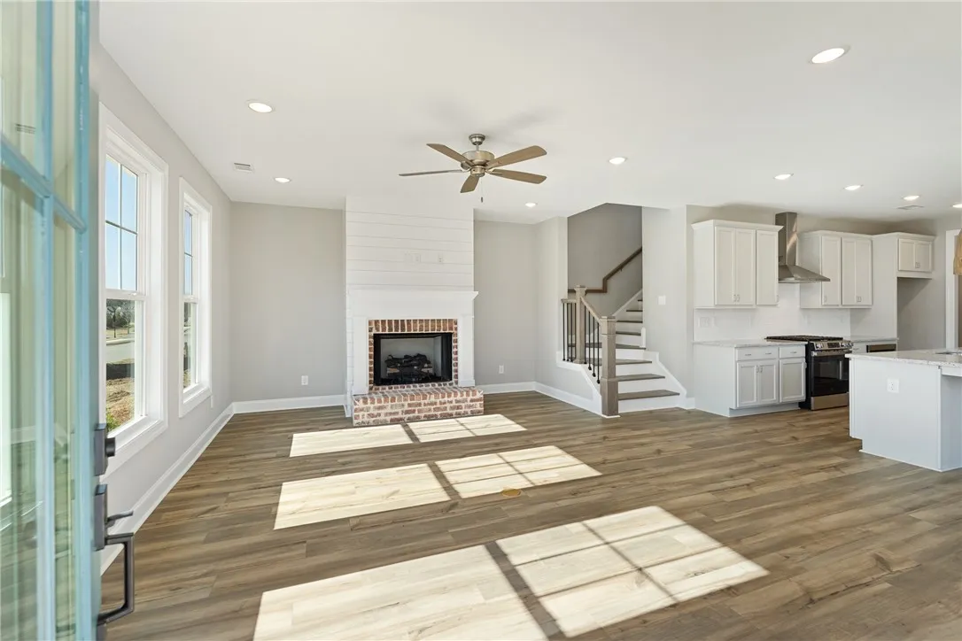 This airy open-concept living space features a cozy fireplace, sleek kitchen, and direct access to upper levels. Photos are not of subject property. Photos are of the same floorplan of a completed home.