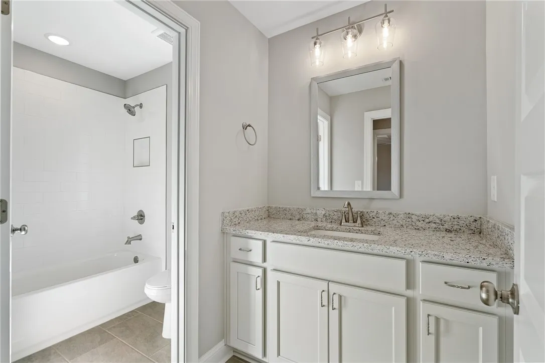 This clean and bright bathroom features a vanity with ample counter space and a modern tub and shower. Photos are not of subject property. Photos are of the same floorplan of a completed home.
