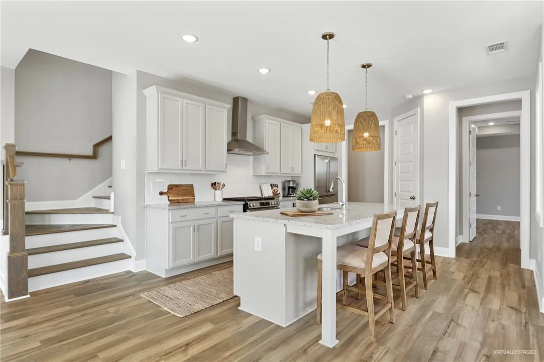 This bright kitchen features a functional island and hardwood floors. Photos are not of subject property. Photos are of the same floorplan of a completed home.