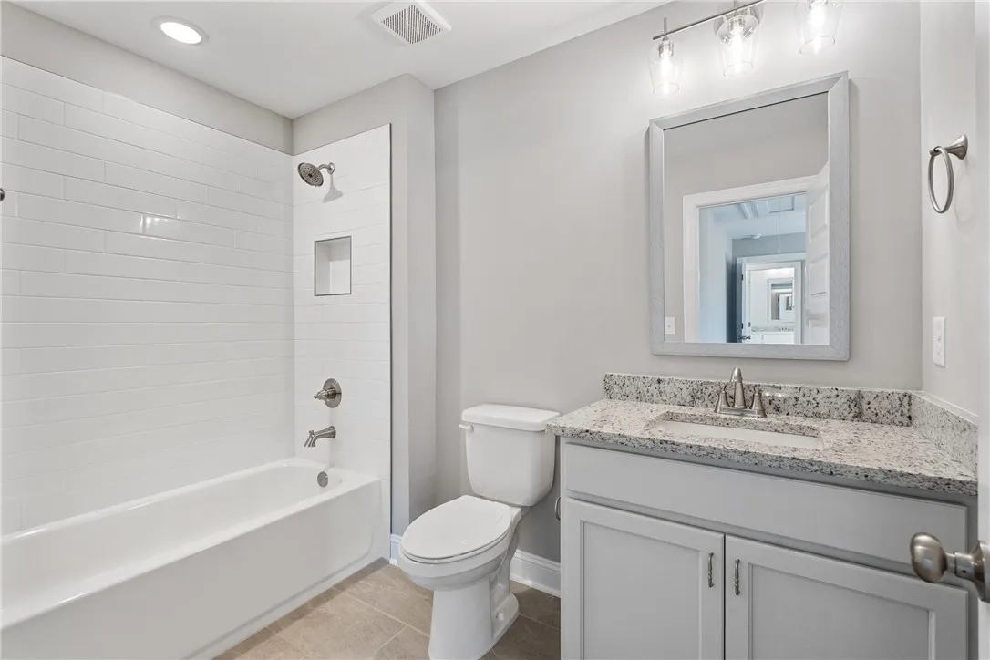 This bright bathroom features sleek tile flooring and a functional vanity with ample counter space. Photos are not of subject property. Photos are of the same floorplan of a completed home.