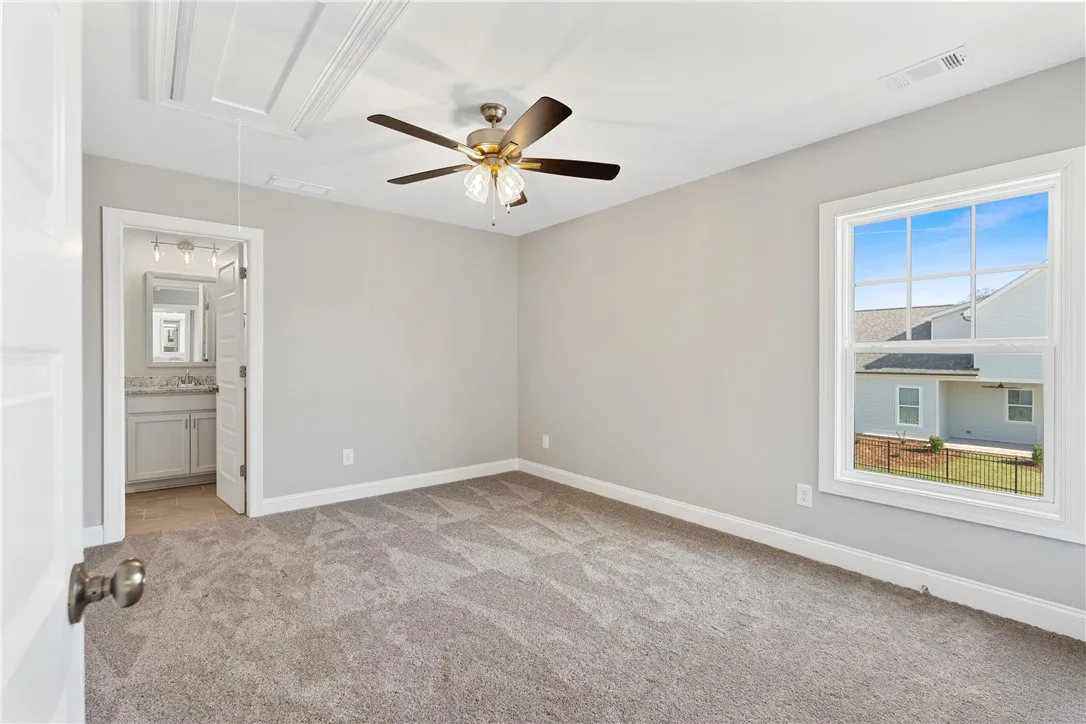 This inviting bedroom features soft carpeting and a window offering views of the neighborhood. Photos are not of subject property. Photos are of the same floorplan of a completed home.