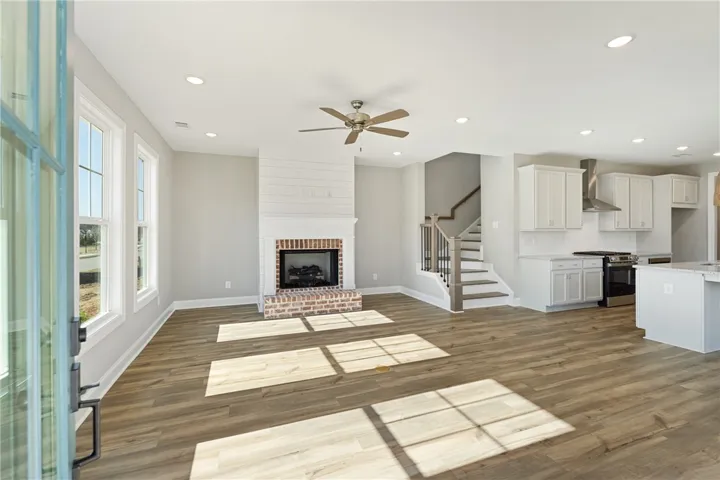 This airy open-concept living space features a cozy fireplace, sleek kitchen, and direct access to upper levels. Photos are not of subject property. Photos are of the same floorplan of a completed home.