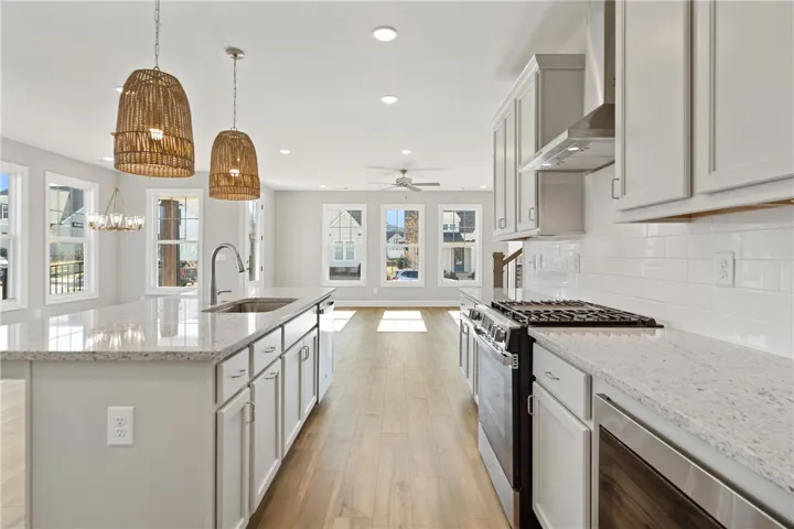 This bright kitchen features an island, ample counter space, and opens to a luminous living area. Photos are not of subject property. Photos are of the same floorplan of a completed home.