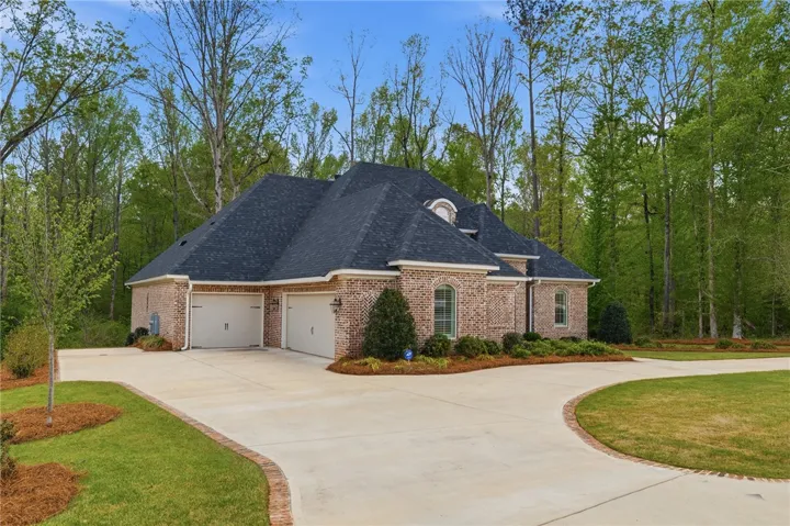 A circular drive lined in brick, a third garage bay, and an additional parking pad provide ample space for vehicles.