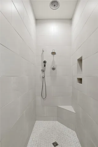 Zero-entry shower with ceiling-height tile and three shower heads.