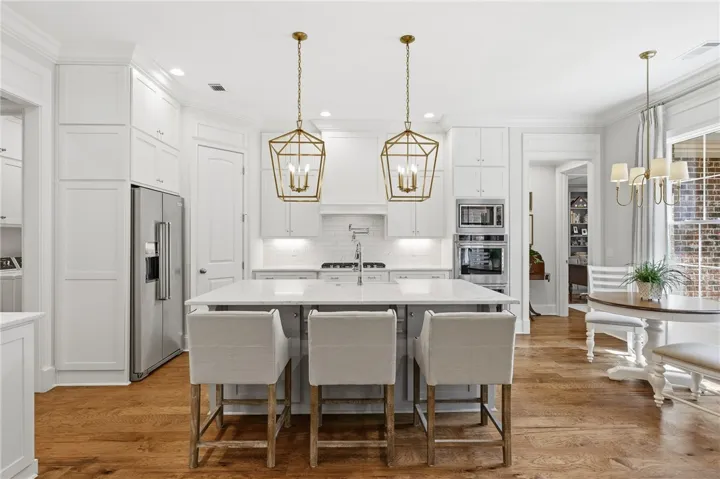 Well-appointed kitchen featuring ceiling-height cabinetry, marble countertops, ample storage, KitchenAid appliances, pantry, and a breakfast nook.