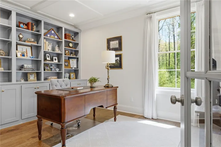 Bedroom 2, located beyond the kitchen, is staged as an office with wall-to-wall ceiling-height built-ins.
