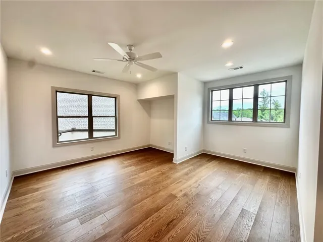 The second-floor bonus room/bedroom features hardwood flooring, multiple windows for natural light, and versatile space for a range of needs.