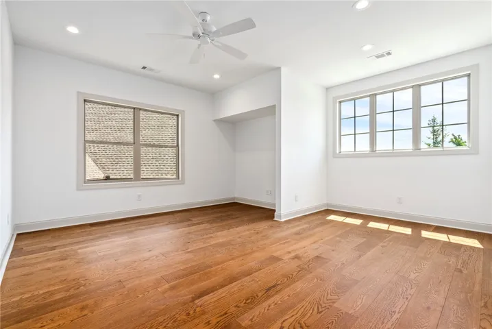 The second-floor bonus room/bedroom features hardwood flooring, multiple windows for natural light, and versatile space for a range of needs.