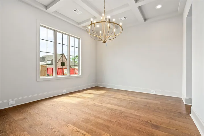 A coffered ceiling, stunning chandelier, and large window in the formal dining room create a lovely first impression.