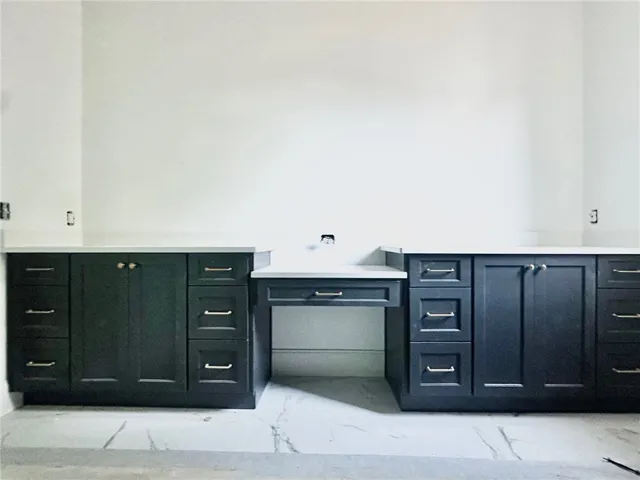 The primary bath's extended vanity offers dual sinks and a dressing table. A zero-enty tiled shower is beyond.