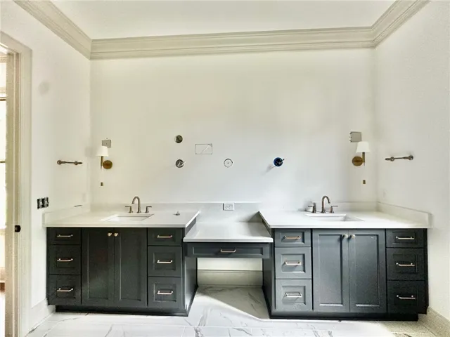 The primary bath's extended vanity offers dual sinks and a dressing table. A zero-enty tiled shower is beyond.