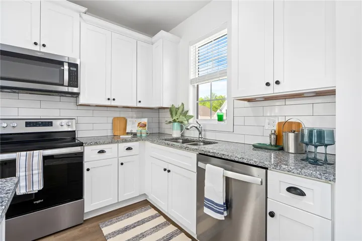 Delta plumbing, granite countertops, and subway tile backsplash create a clean and classic kitchen.