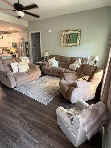 This inviting living area features durable flooring, an open layout, and a cooling ceiling fan.