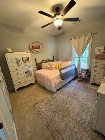 This cozy bedroom features plush carpeting and a bright window, creating a serene and comfortable retreat.