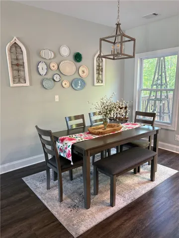 This inviting dining area features dark wood flooring and ample natural light, creating a comfortable ambiance.