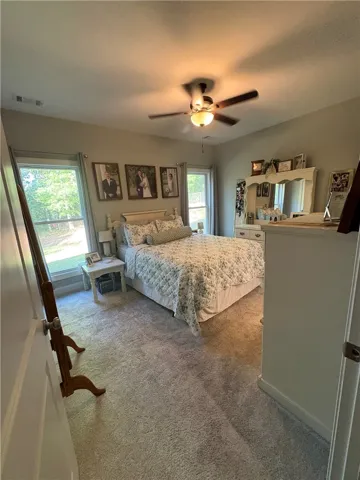 This restful bedroom offers a comfortable retreat with soft carpet flooring and ample natural light.
