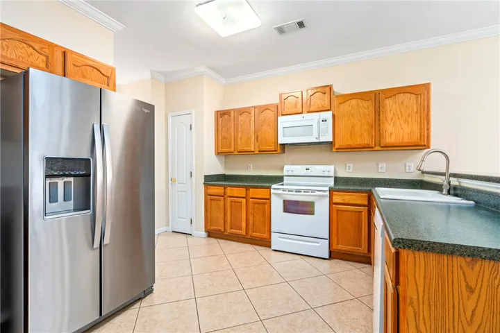 A well-appointed kitchen features tile flooring, pantry, plenty of cabinets. durable countertops, and appliances.