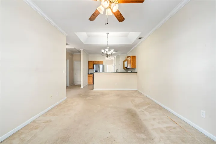 An open floorplan living area flows seamlessly into the breakfast room area and kitchen, illuminated by both a chandelier and ceiling fan.