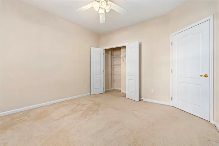 Bedroom #2 offers ample storage with a double-door closet and soft carpeting underfoot, and ceiling fan.