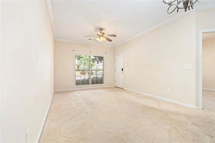 Front view of living room features light-toned carpeting and a large window for natural light. All window blinds remain