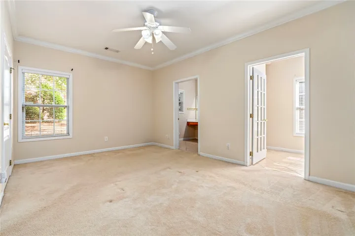 An airy, well-lit Master bedroom suite is large - features plush carpeting, ceiling fan and walk-in spacious closet. French doors open to flex space.