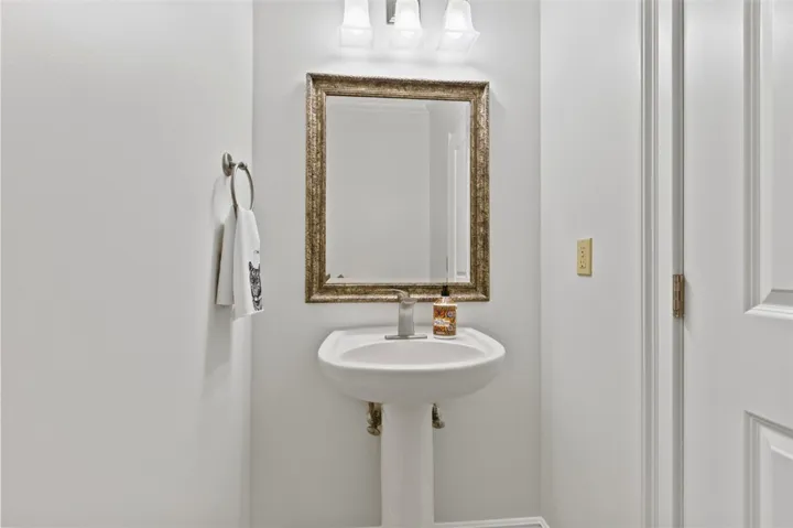 This half bathroom features a sleek pedestal sink paired with a stylish framed mirror.
