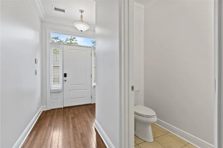 This entry welcomes with warm flooring and a convenient half bath, perfect for guests.