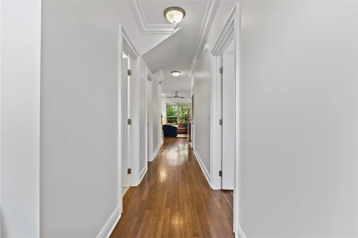 This bright hallway showcases rich wood flooring and leads to sunlit living areas.