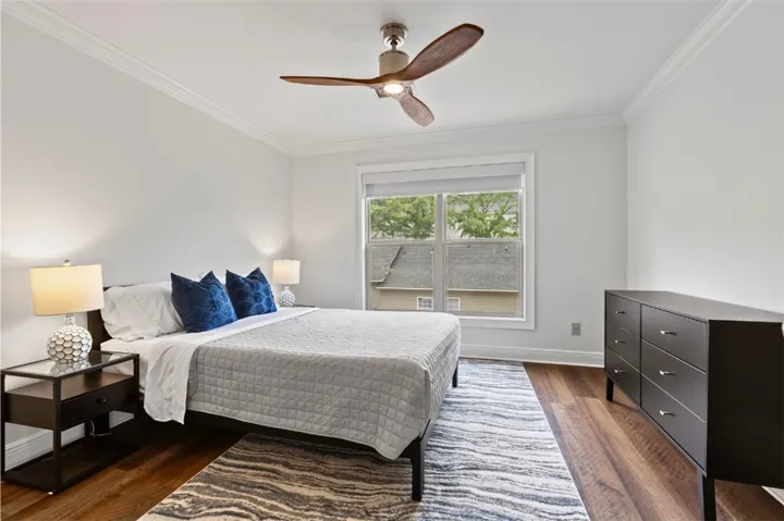 This serene upstairs guest bedroom offers ample light and comfort with beautiful wood flooring.