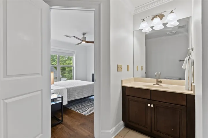 This bright upstairs guest bathroom features a vanity with ample storage and a clear view into the adjacent bedroom.