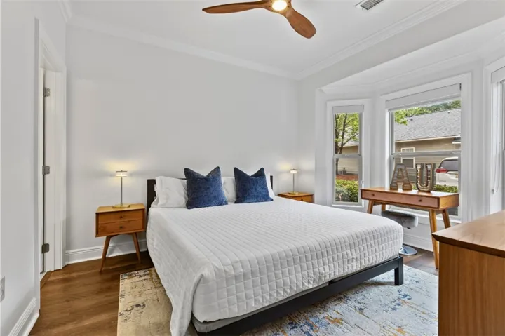 This bright and inviting downstairs bedroom features warm wood flooring and elegant crown molding, creating a comfortable retreat with large walk-in closet.