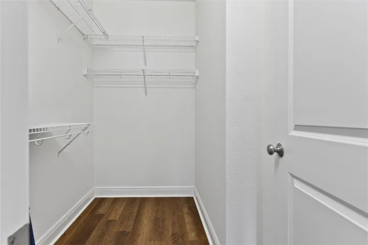 This spacious walk-in closet features ample wire shelving and beautiful wood flooring.