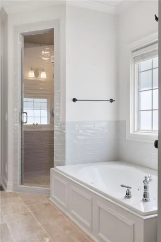 This serene bathroom offers a spacious soaking tub and a sleek glass-enclosed shower.