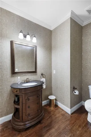 This exquisite bathroom showcases hardwood flooring and elegant crown molding, creating a refined atmosphere.