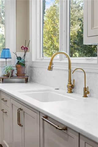 This bright kitchen features elegant gold fixtures and a spacious sink for everyday use.