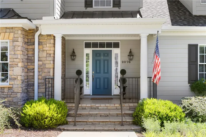 The welcoming entrance features a charming stone facade and a striking blue front door.