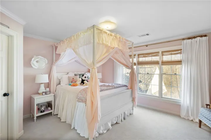 This serene room features ample natural light, soft wall colors, and classic crown molding.