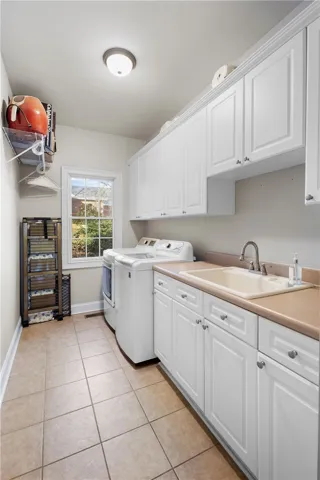 This functional laundry area features abundant cabinetry and a convenient _utility sink.